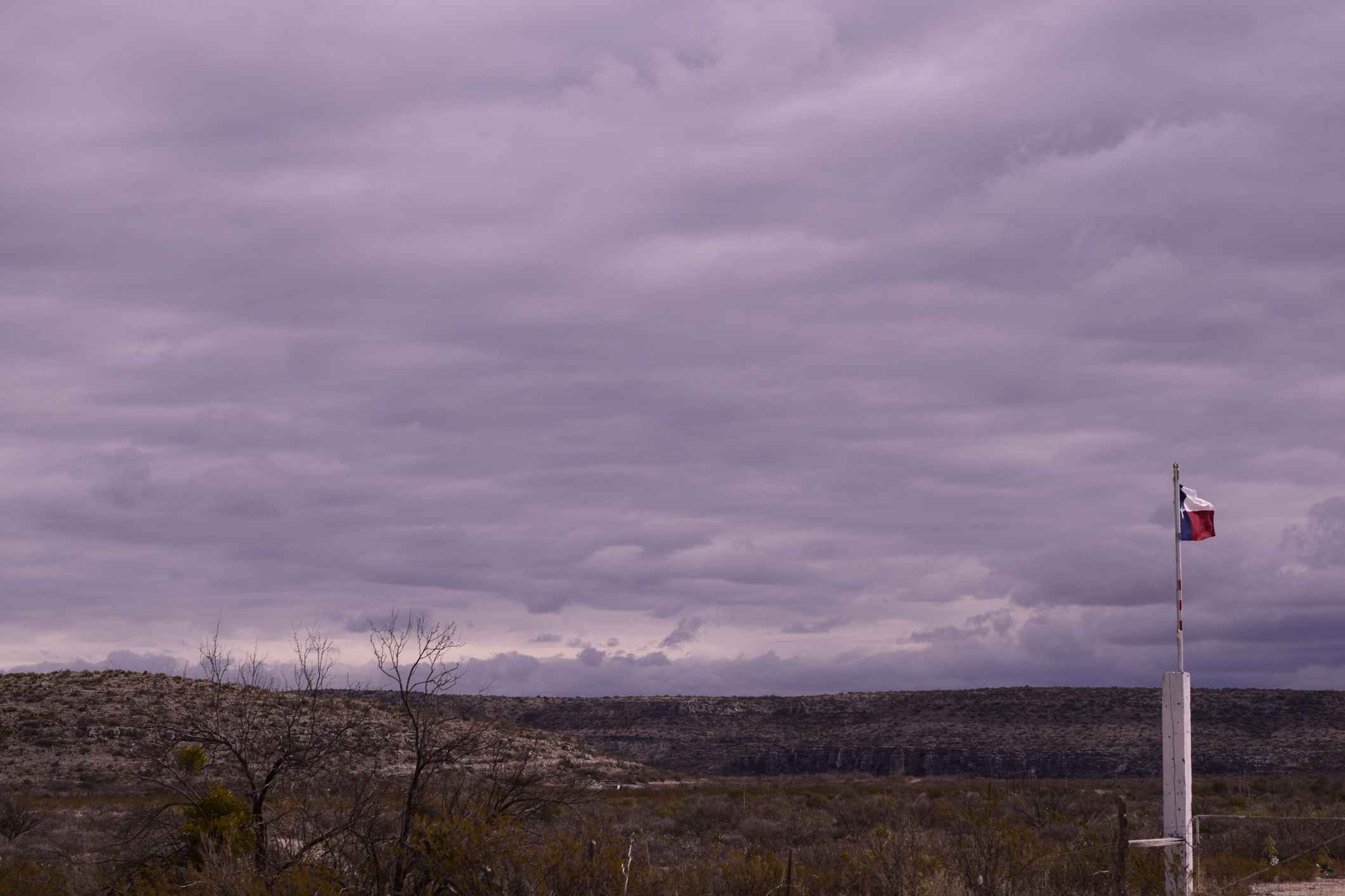 Beautiful Western Texas Desert Landscape With Waving Texas Flag Against Dramatic Storm Clouds