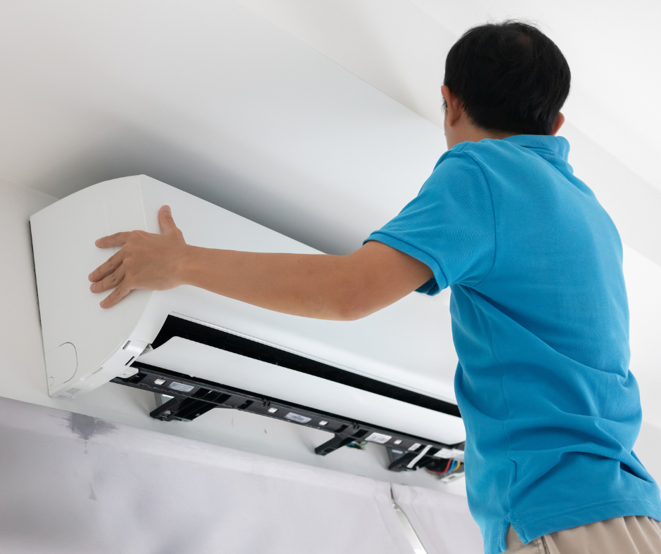 HVAC technician in blue shirt working on a ductless mini split