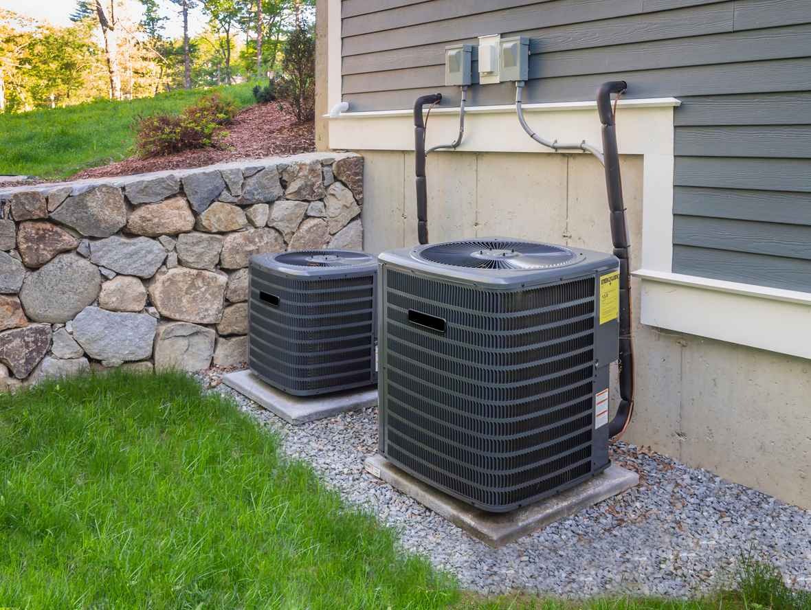 Two outdoor air conditioning units on the side of a home