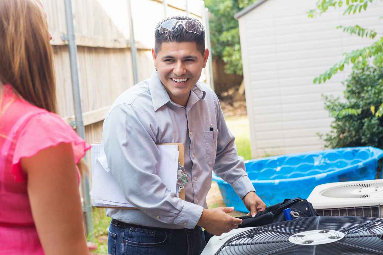 Air conditioner repairman explaining A/C damage to homeowners