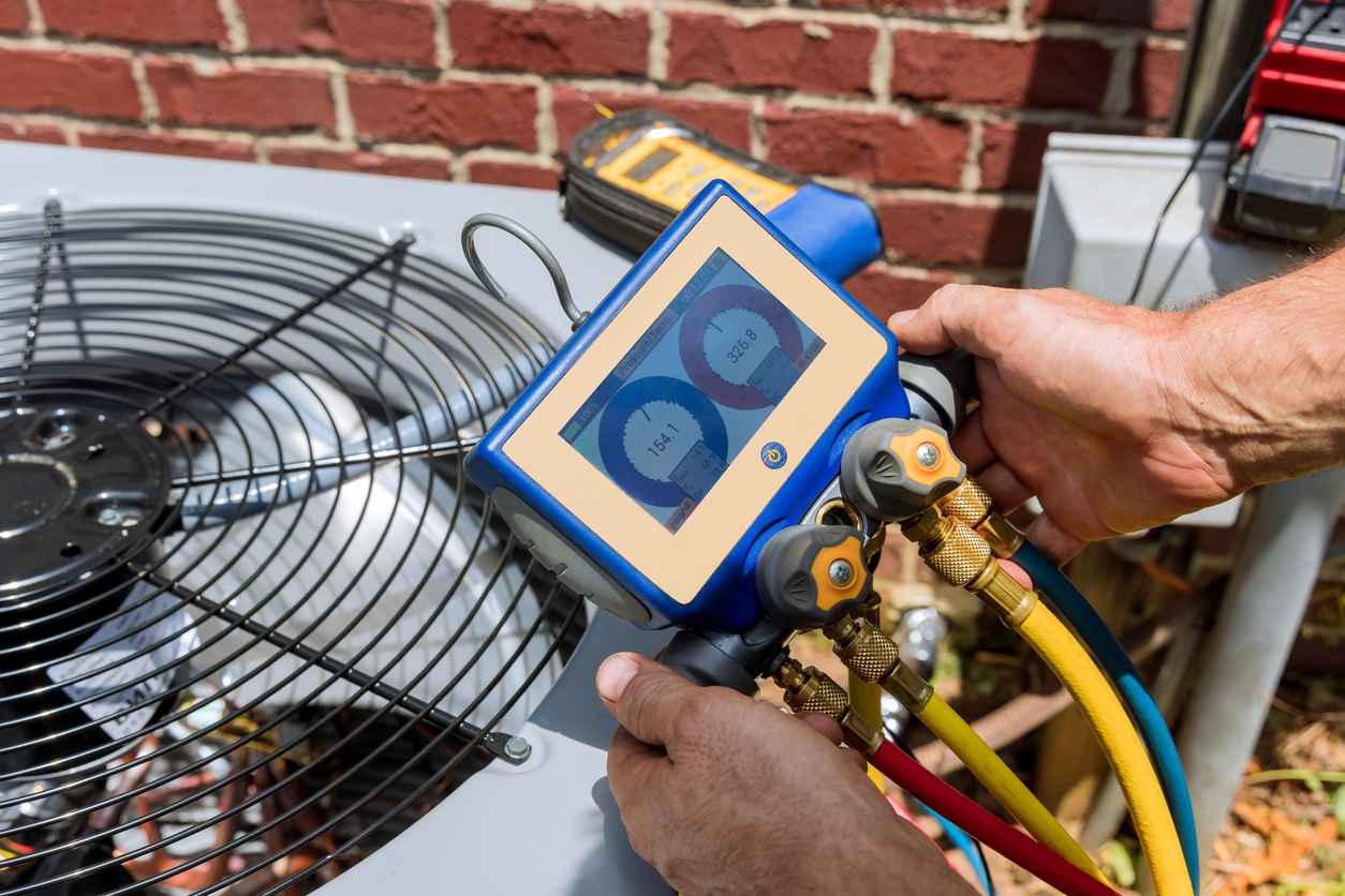 HVAC technician servicing outdoor AC unit, checking refrigerant levels