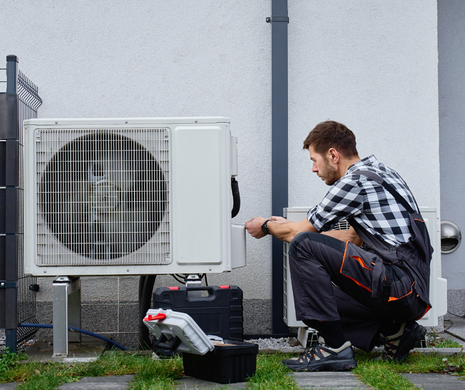 HVAC technician working on heat pump outside of a residential home