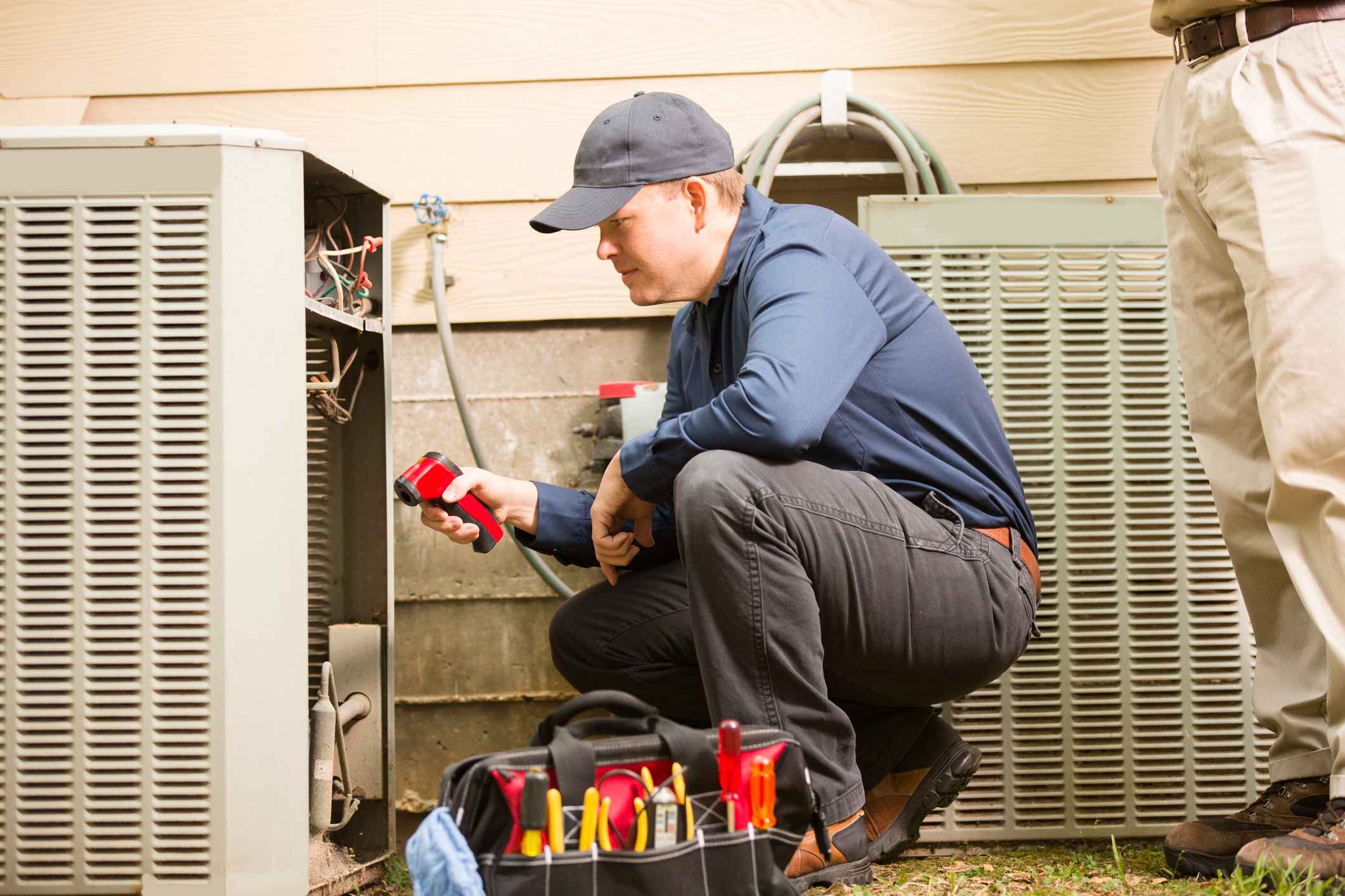 Male HVAC technician working on a home's outdoor AC unit